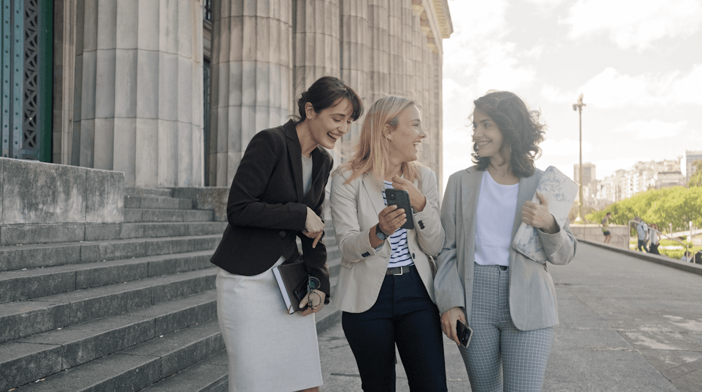 Three law students laughing together on the steps of a courthouse