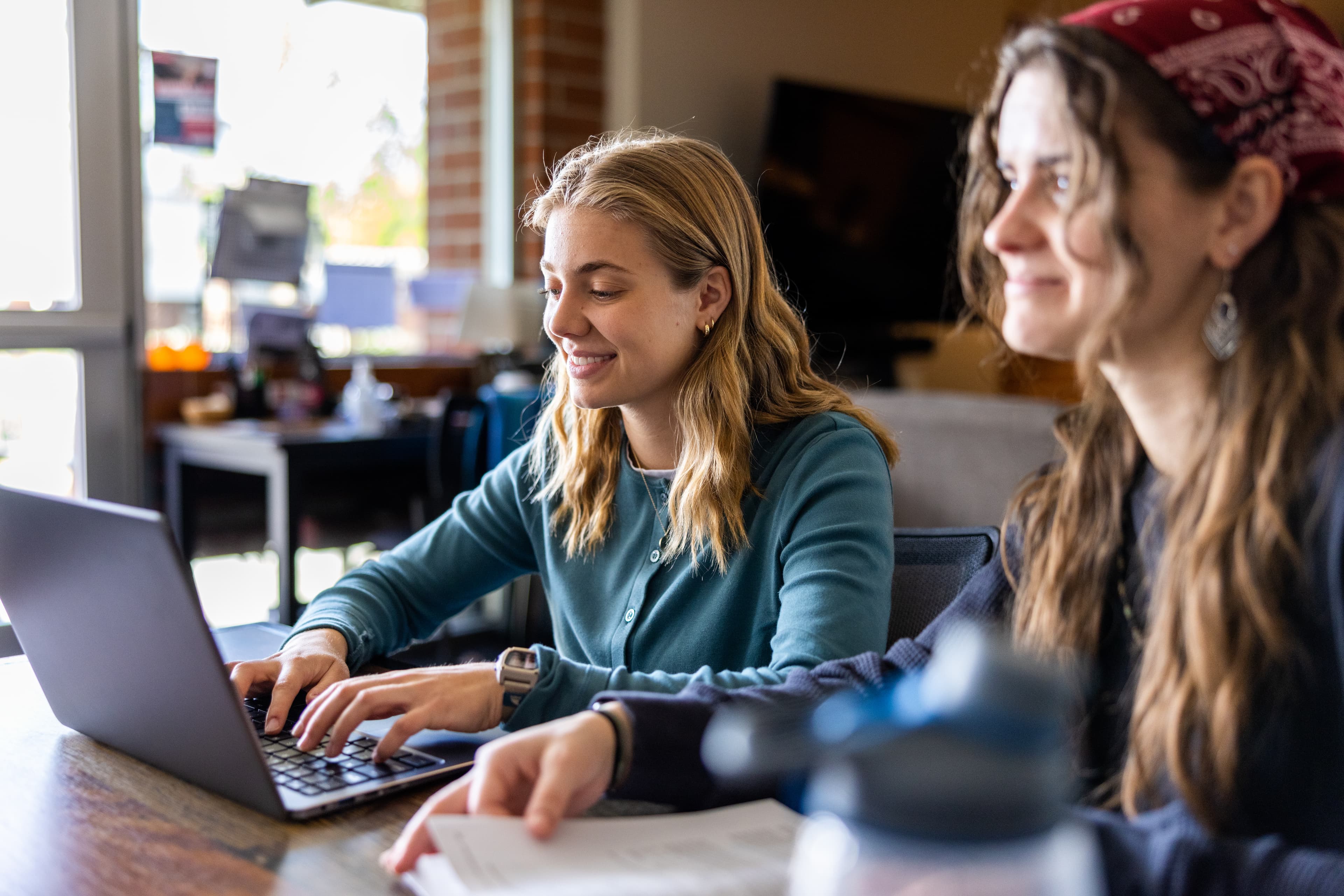 Two students smiling while studying together at a laptop
